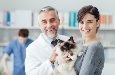 Smiling woman and her cat at the veterinary clinic